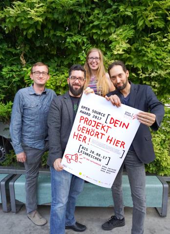 Gruppe von 4 Personen. 2 Personen halten gemeinsam ein Plakat es Open Minds Awards in die Kamera